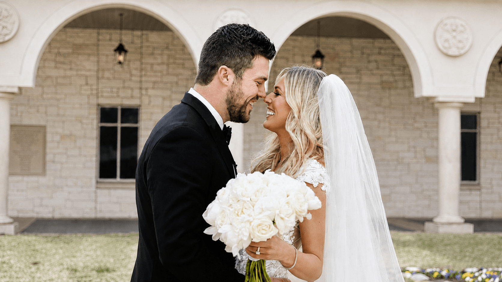 Wedding couple walking beneath a stone archway